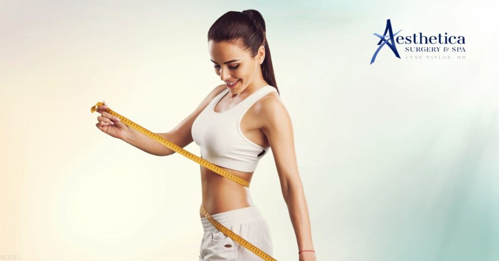 Slim woman holding measure tape around her body. (MODEL) Anne Taylor, MD: Aesthetica Surgery & Spa Logo