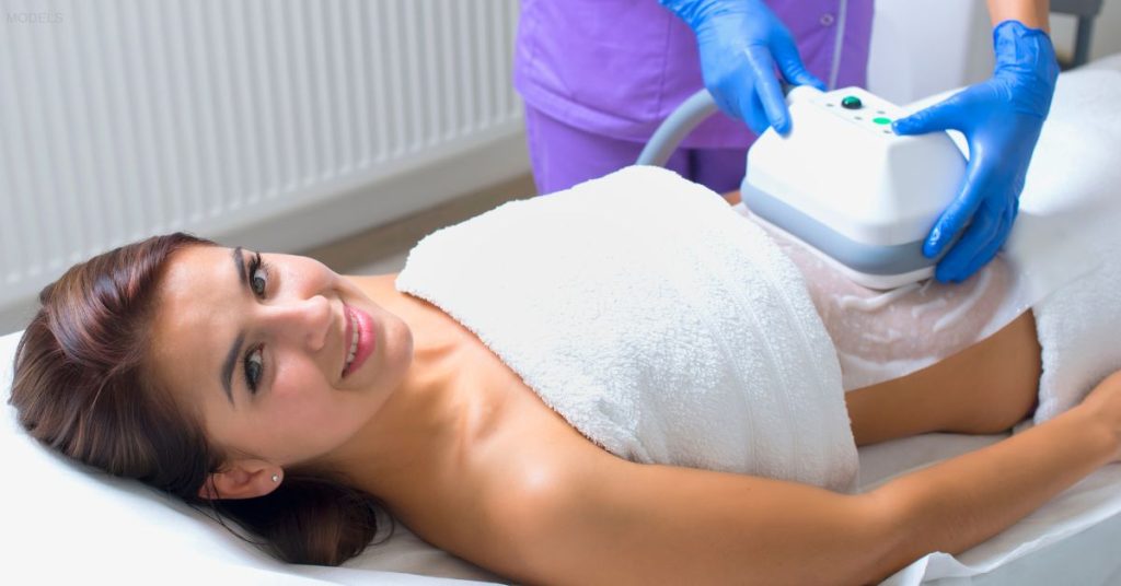 Pretty young woman getting cryolipolyse treatment in cosmetic cabinet. (MODEL)