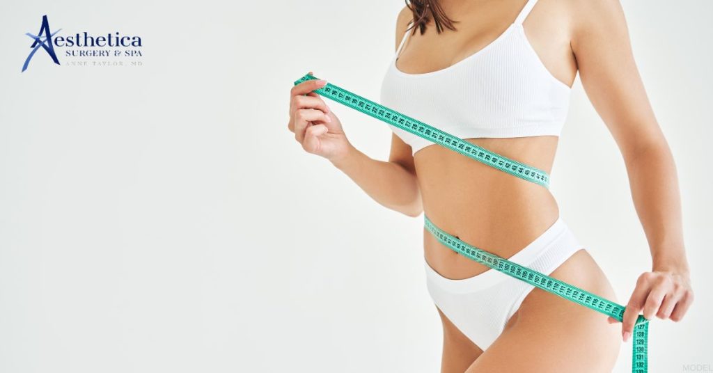 Slim woman holding measure tape around her body (MODEL). Anne Taylor, MD: Aesthetica Surgery & Spa Logo