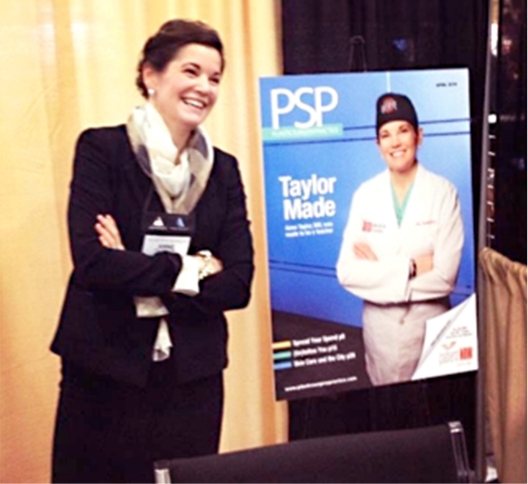 Dr. Anne Taylor posing for a photograph in next to a large image of her magazine cover.